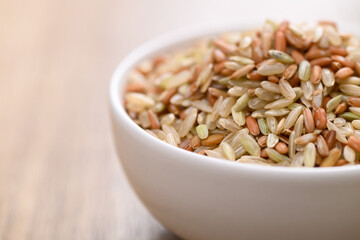 Organic Thai highland brown rice grain in a bowl on wooden table (Cargo rice, Loonzain rice or Husked rice), Healthy food