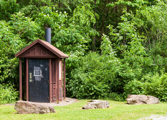 An outhouse in the woods in Warren County, Pennsylvania, USA on a sunny summer day
