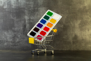 school paints in a shopping cart on a dark background,