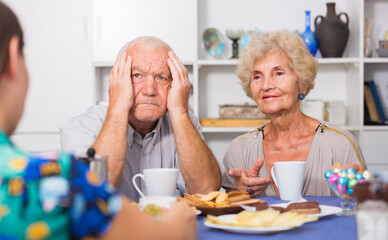 Stressed senior couple having conversation with female over cup of coffee at home