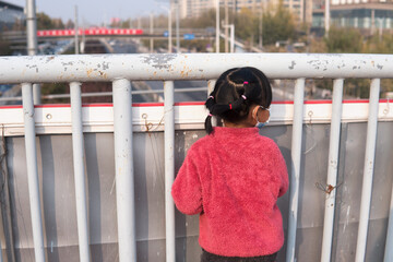 A girl wearing a mask looks down on the flyover