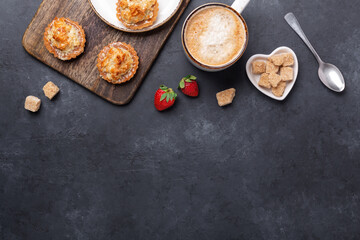 Obraz na płótnie Canvas Coffee, cakes, strawberries on a wooden cutting board. Dark stone table. Tasty breakfast. Top view. Copy space