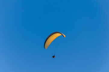 A man on a paraglider against the sky.