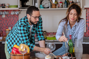 Pareja de jóvenes tienen un momento de relax en la cocina mientras preparan la cena para disfrutar...
