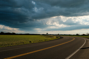 Fototapeta premium Curved road with dramatic summer storm clouds
