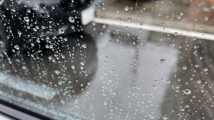 水滴のたくさんついた車の窓ガラスと雨に濡れた道路と対向車