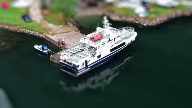 N&aelig;r&oslash;yfjorden Camping  (Dyrdal Gard) in Bakka, Norway from above. Mobile homes, vans, and tents scattered on the grass. A small ferry and motorboats moored at the dock. The fjord is calm and mirrorlike