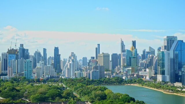 Stationary time-lapse of downtown Bangkok city skyline, cityscape, and the skyscrapers of the business district, Benjakitti Park, CTI Tower. Wide panoramic distant view daytime cloudy sky