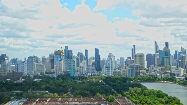 Clouds timelapse over Bangkok cityscape daytime from a high point, numerous skyscrapers of downtown business district, Benjakitti Park, CTI Tower, Queen Sirikit National Convention Centre construction