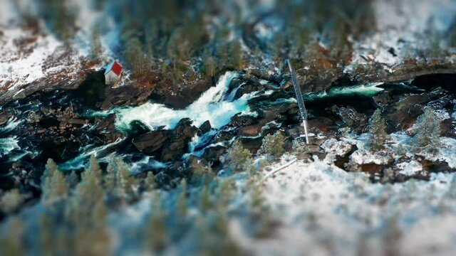 Likholefossen waterfall in Gaular, Norway. Raging whitewater whirling and splashing, fed by the melting snow in the mountains. A still bridge crossing the river. A tilt-shift video.
