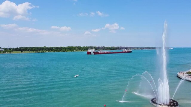 Large ship cruising through the Detroit River past a fountain