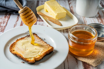 Preparing a healthy breakfast with a toast with butter and pure organic honey from bees.