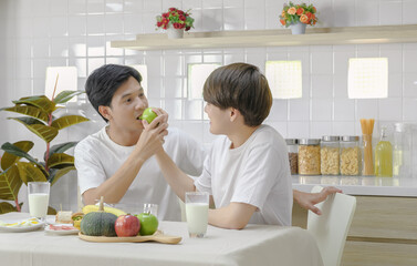 Affectionate asian young LGBT gay couple enjoy eating breakfast together in sweet moment on holiday weekend at home. Selective focus.