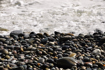 A wave breaking on a pebble beach, close-up. Background image