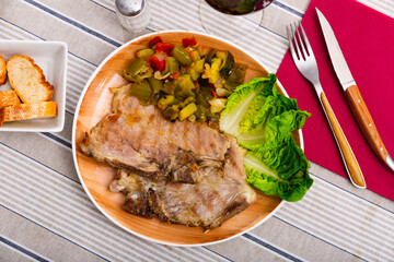 Delicious juicy roast pork with stewed vegetables, garnished with lettuce leaves on a plate
