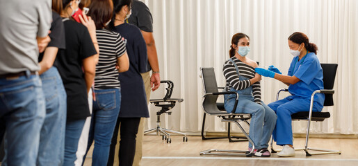 Citizens of different ages in a row standing and waiting for a vaccine injection while medical people injecting to young woman in face mask. Covid-19 or coronavirus vaccination service concept - obrazy, fototapety, plakaty
