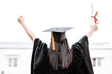Woman in gowns raise their hands show signs of happiness after graduation with a graduation...