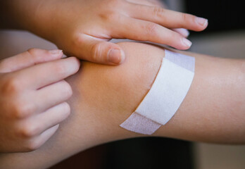 A little boy sticks a Band-Aid on the damaged skin on his leg.An abrasion and a scratch on the knee.