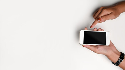 Top view woman holding smart phone with blank screen on white background.