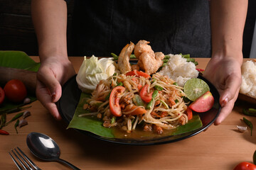 Woman holding plate of spicy papaya salad.