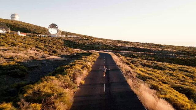 Man running over empty road with big scientific buildings in the background