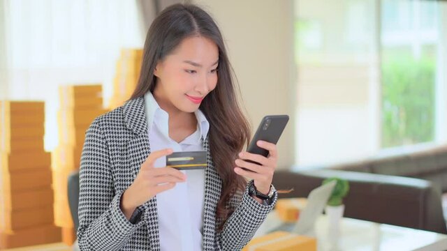 A young woman double checks the number of her credit card against her smartphone entry. Title space