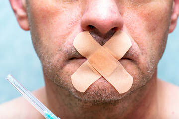 the concept of universal vaccination and freedom of speech a person's mouth is sealed with a medical plaster next to a syringe for injection