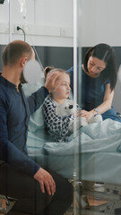 Sick daughter wearing oxygen nasal tube lying in bed after illness surgery waiting for medical examination with parents in hospital ward. Hospitalized child recovering after flu isickness nfection