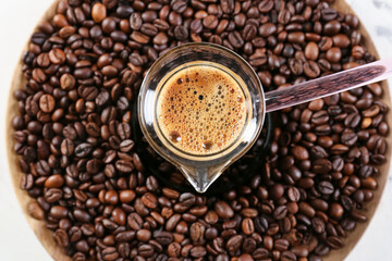 Pot with delicious turkish coffee and plate with beans on light background