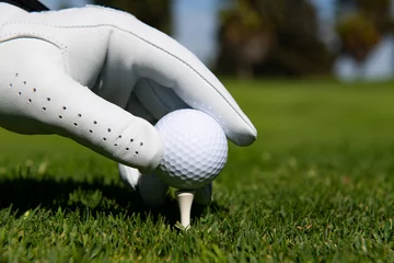 Foto auf Acrylglas Golf ball on green course. Hand putting golf ball on tee in golf course. © Volodymyr