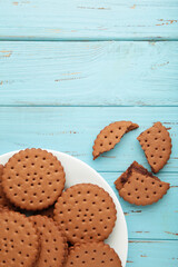 Chocolate chip cookie on white plate on blue wooden background. Top view.