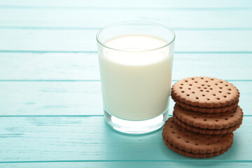 Chocolate chip cookie and glass of milk on blue wooden background. Top view.