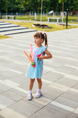 In a public park, a little girl blows and catches soap bubbles.The child is playing and laughing.