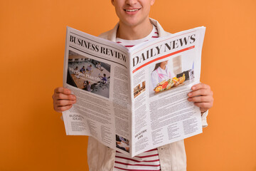 Young man reading newspaper on color background