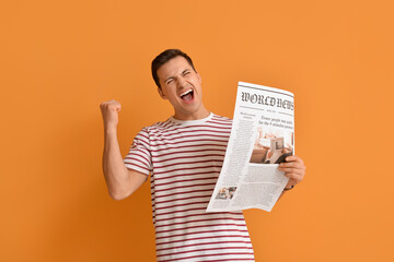 Happy young man with newspaper on color background