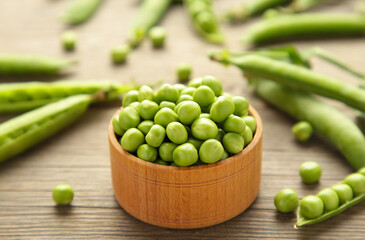 Green peas in wooden bowl on grey background.