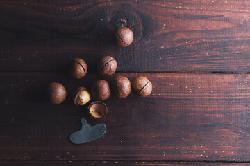 Delicious brown round macadamia nuts and a nut opener key on the brown table