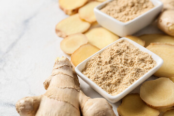 Ginger powder and fresh roots on light background, closeup