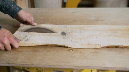Saws wood with a modern circular saw in a workshop. A carpenter is sawing a board on a saw.