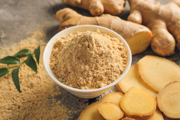 Bowl with ginger powder on grunge background, closeup