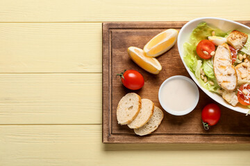 Plate with delicious Caesar salad on color wooden background