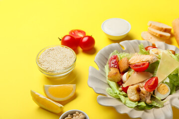 Plate of tasty Caesar salad and ingredients on color background