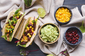 Composition with tacos and tasty guacamole on dark wooden background
