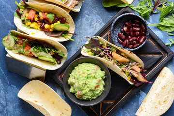 Composition with tacos and tasty guacamole in bowl on color background