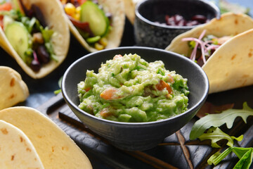 Tasty guacamole in bowl and tacos, closeup