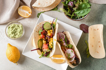 Plate with tacos and tasty guacamole in bowl on color background
