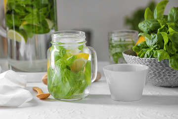Mason jar of lemonade with basil on table in kitchen