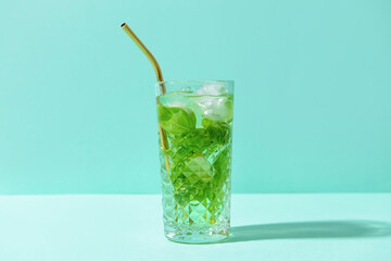 Glass of lemonade with basil on color background