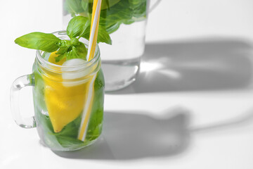 Mason jar of lemonade with basil on light background