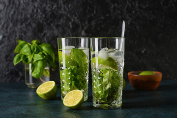 Glasses of lemonade with basil on dark background